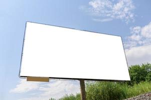 cartelera blanca en blanco con espacio para agregar su propio texto. fondo con nubes blancas y cielo azul para publicidad exterior, pancartas con camino de recorte foto