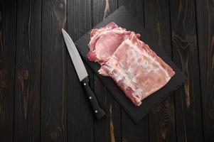 A large piece of pork loin on a rustic dark background. photo