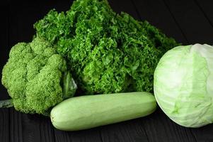 Still life of green vegetables on black background photo