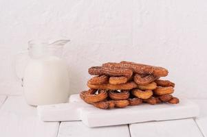 churros caseros con leche y nata sobre un fondo blanco de madera. foto