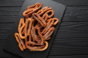 Homemade churros on a wooden black background. photo