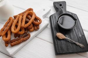 Homemade churros with chocolate on a white wooden background. photo