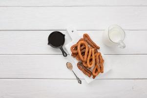 Homemade churros with chocolate on a white wooden background. photo