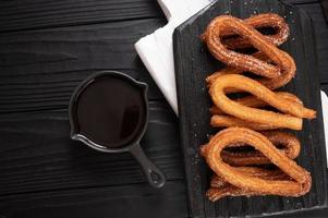 Homemade churros with chocolate on a dark wooden rustic background. photo