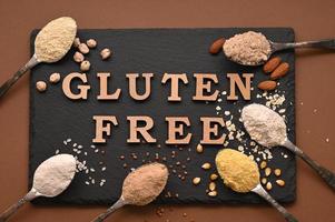 Gluten free text and spoons of various gluten free flour, almond, buckwheat, rice, corn, oat, chickpea. Flat lay, top photo