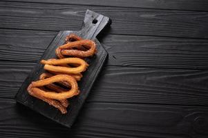 churros caseros sobre un fondo negro de madera. foto