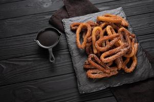 churros caseros con chocolate sobre un fondo rústico de madera oscura. foto