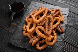 churros caseros con chocolate sobre un fondo rústico de madera oscura. foto