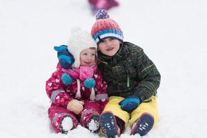 grupo de niños divirtiéndose y jugando juntos en la nieve fresca foto