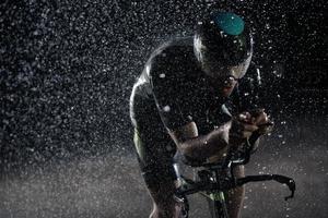 triathlon athlete riding bike  fast on rainy night photo