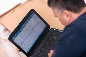 man using laptop while lying on cardboard box photo