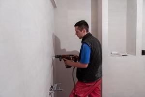 construction worker drilling holes in the bathroom photo