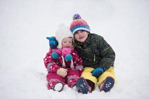 grupo de niños divirtiéndose y jugando juntos en la nieve fresca foto