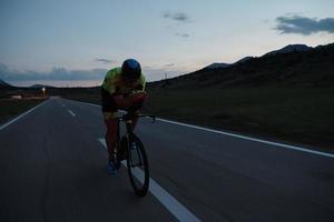 atleta de triatlón montando bicicleta por la noche foto