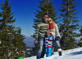 familia divirtiéndose en la nieve fresca en las vacaciones de invierno foto