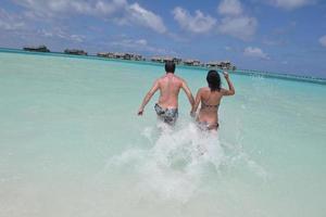 feliz pareja joven divertirse en la playa foto