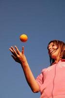 mano femenina equilibrando naranja en el aire foto