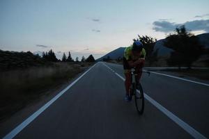 atleta de triatlón montando bicicleta por la noche foto