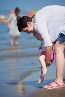 mamá y bebé en la playa se divierten foto