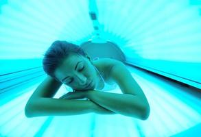 Beautiful young woman tanning in solarium photo