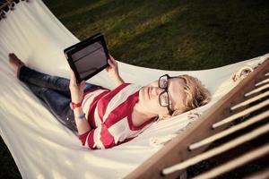 woman using a tablet computer while relaxing on hammock photo