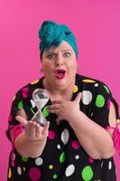 Portrait of plus size young lady smiling hands holds sand clock isolated on pink color background. photo