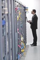 businessman with laptop in network server room photo