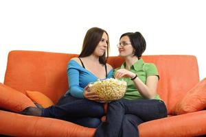 amigas comiendo palomitas de maíz y viendo la televisión en casa foto