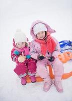 portrait of two little girls sitting together on sledges photo