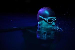 authentic triathlete swimmer having a break during hard training on night neon gel light photo