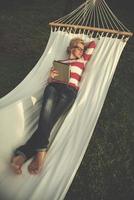 woman using a tablet computer while relaxing on hammock photo