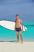 hombre con tabla de surf en la playa foto