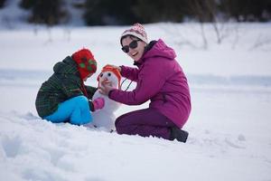 familia feliz construyendo muñeco de nieve foto