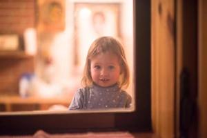 niña linda jugando cerca de la ventana foto