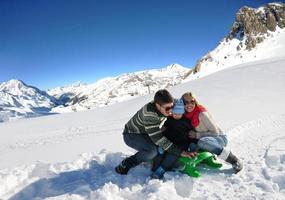 family having fun on fresh snow at winter vacation photo