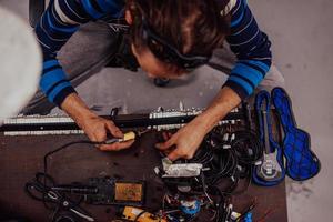 Industrial worker man soldering cables of manufacturing equipment in a factory. Selective focus photo