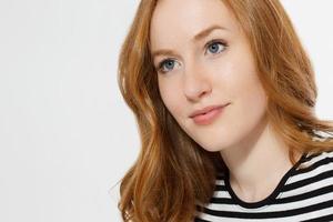 Red haired girl with close up macro face isolated on white background. Woman beauty and skin care. No make up concept. Redhead beautiful female. Selective focus photo