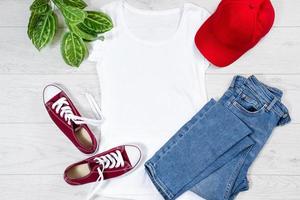 T shirt white and sneakers. T-shirt Mockup flat lay with summer accessories. Baseball Hat, bag, yellow flip flops on wooden floor background. Copy space. Template blank canvas. Front top view. photo