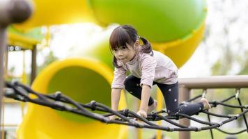 Asian little girl enjoys playing in a children playground, Outdoor portrait photo