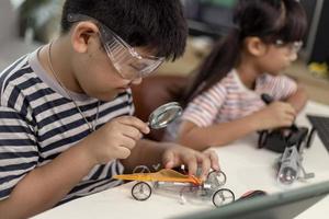 two Asian children having fun learning coding together, learning remotely at home, STEM science, homeschooling education, fun social distancing, isolation, new normal concept photo