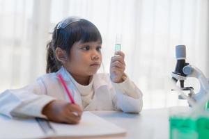 education, science, chemistry, and children concept - kids or students with test tube making experiment at school laboratory photo