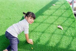 Cute Asian girl having fun trying to climb on artificial boulders at schoolyard playground, Little girl climbing up the rock wall, Hand Eye Coordination, Skills development photo