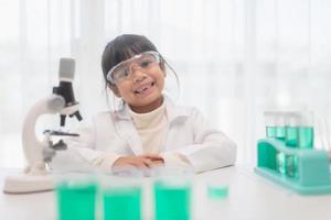 education, science, chemistry, and children concept - kids or students with test tube making experiment at school laboratory photo
