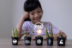 Little girl watching a plant. Environmental technology concept. Sustainable development goals. ESG. photo