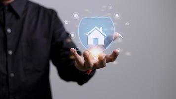 House or Family Insurance Concept. Company Supporting and Protecting their Customer by Shield, Home Icon floating over a Careful Gesture Hand of a Businessman photo