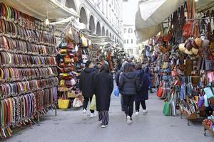 Florence, Italy, 2019 - Tourists walk past the large display of leather belts of the street vendors in Florence, Italy. photo