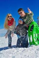 familia divirtiéndose en la nieve fresca en invierno foto