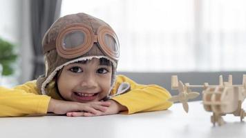 Asian little girl at home plays with a toy plane, she wants to become a pilot. Dreamer pilot. photo