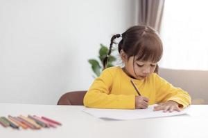 niño asiático haciendo la tarea en casa. foto