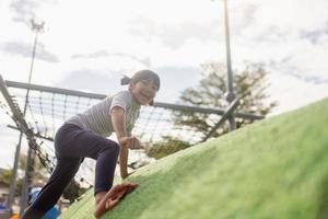 Cute Asian girl having fun trying to climb on artificial boulders at schoolyard playground, Little girl climbing up the rock wall, Hand Eye Coordination, Skills development photo